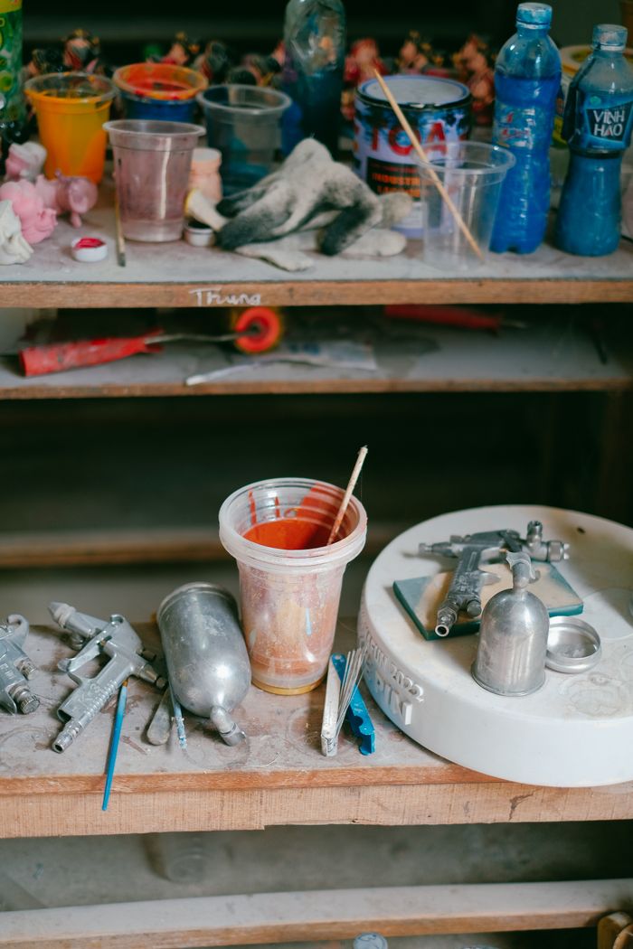 A messy workshop bench filled with colorful paints, brushes, and tools for artistic projects.
